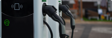 Borne de recharge pour voitures électriques de niveau 2, située dans un cadre urbain, avec des véhicules électriques branchés et en cours de charge.
